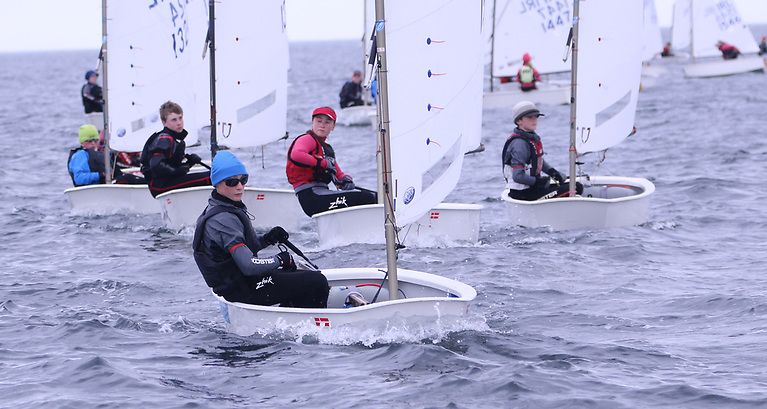 Solo young sailor, smiling, on a dinghy.